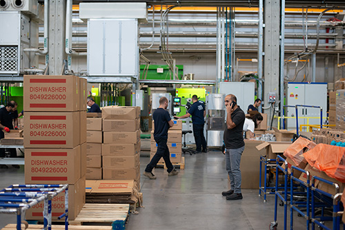 Warehouse with workers doing different jobs. Man in foreground on telephone. 